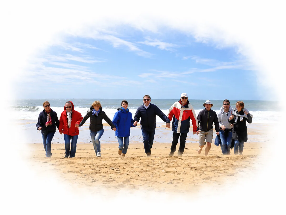 Un groupe de personnes courant main dans la main sur une plage, au bord de l'eau